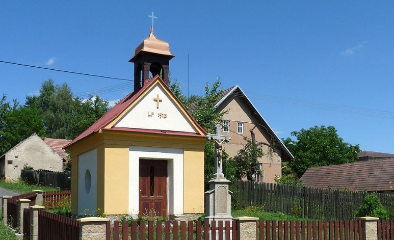 Kaple s kamenným křížem uprostřed obce
